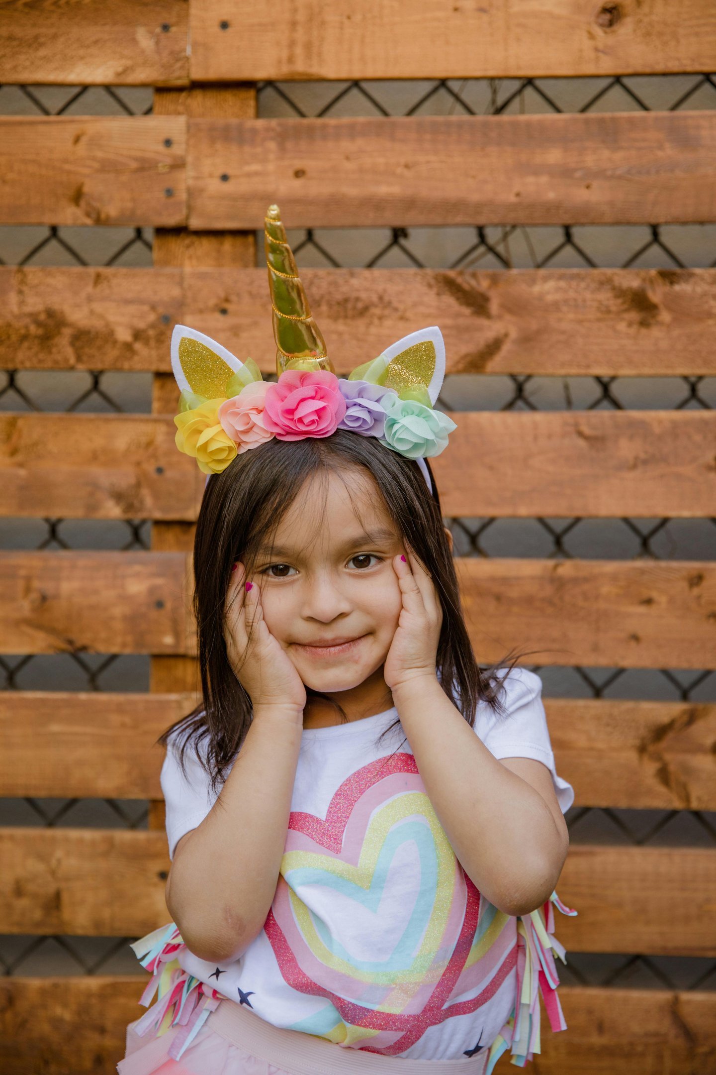 Little girl with hands on face wearing a unicorn headband